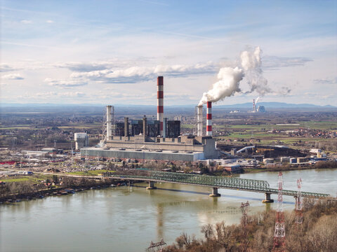 Aerial view of Termal Power Plant Nikola Tesla A with its tall chimneys emitting smoke, situated along the Sava river with a metal bridge, Urovci, Grad Beograd, Serbia.