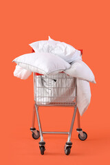 Shopping cart full of pillows on orange background © Pixel-Shot