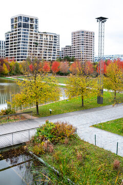 Autumn park and modern apartments in Clichy-Batignolles Paris France show landscaped urban development around water and seasonal trees