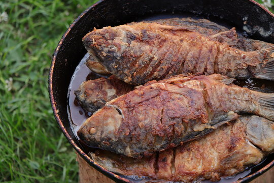 Close up of crispy pan fried freshwater fish served in vintage frying pan