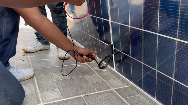Technician testing the electrical output of a solar panel with a digital multimeter.