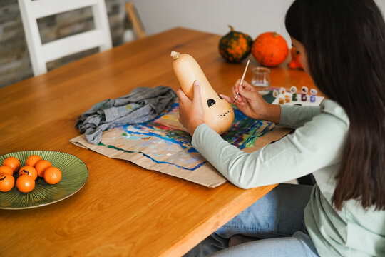 Female kid painting a pumpkin for an halloween party fest - Holidays and art concept - Main focus on left hand - UGC content