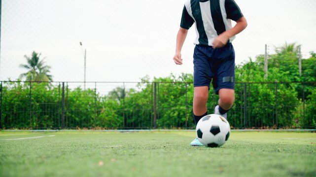 Kid boy leg kicking soccer ball on green grass field action. conceptual metaphor for youth sports training team competition fitness health wellness and active lifestyle	