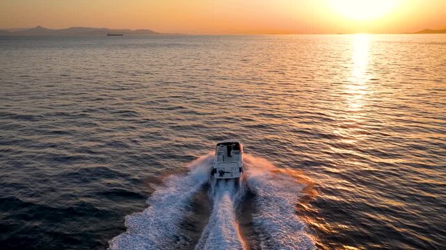 Rear view of a sports motor boat cruising with high speed into the colorful sunset