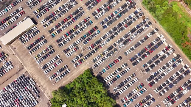 Aerial view of rows of new cars parked in a large outdoor storage facility at a manufacturing plant in India.