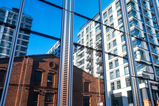Modern residential towers and historic brick architecture appear through reflective glass creating layered urban contrasts in a dense city scene
