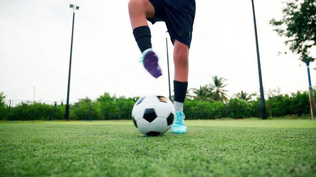 Kid boy leg kicking soccer ball on green grass field action. conceptual metaphor for youth sports training team competition fitness health wellness and active lifestyle	