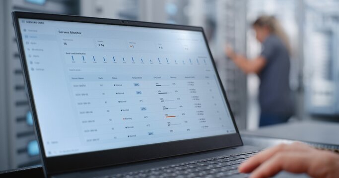 Male Network Engineer Monitors Server Telemetry as Critical Overheating Warning Appears, Analyzing System Metrics and Network Traffic While Responding to Infrastructure Performance Incident.
