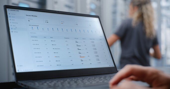 Male Network Engineer Monitors Server Telemetry as Critical Overheating Warning Appears, Analyzing System Metrics and Network Traffic While Responding to Infrastructure Performance Incident.