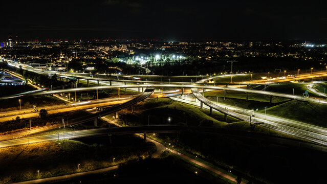 Aerial view of the Westvliet highway intersection at night with illuminated roads and light trails from traffic in Den Haag, Zuid-Holland, Netherlands.
