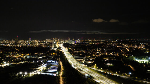 Aerial view of the illuminated Westvliet highway intersection at night with the glowing city skyline of Den Haag in the background, Den Haag, Zuid-Holland, Netherlands.