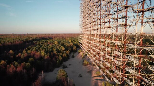 Aerial view of the massive Duga 1 Receiver radar array rising above the dense forest landscape in the exclusion zone of Chernobyl, Kyiv Oblast, Ukraine.