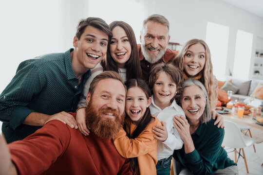Multigenerational family smiling together for a joyful group selfie at home during a cozy celebration