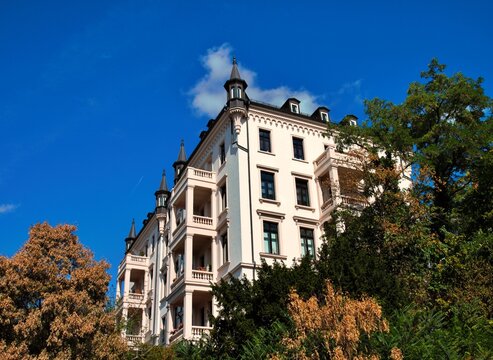 Wiesbaden, Hesse, Germany &ndash; Elegant historic residential building with balconies and decorative turrets surrounded by mature trees.