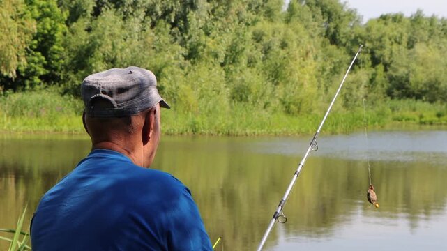 Fisherman casting spin fishing rod on river bank, outdoor activity