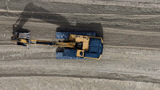 Aerial view of a yellow excavator working on a dirt construction site in Longmont, Colorado, United States.