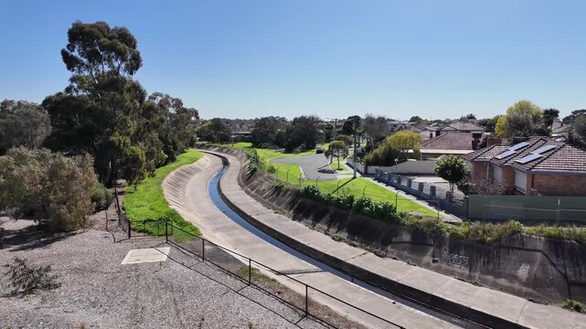Stony Creek flowing through a concrete-lined channel curving through the inner suburb of Yarraville, Melbourne, Victoria, Australia, with established residential housing alongside the waterway