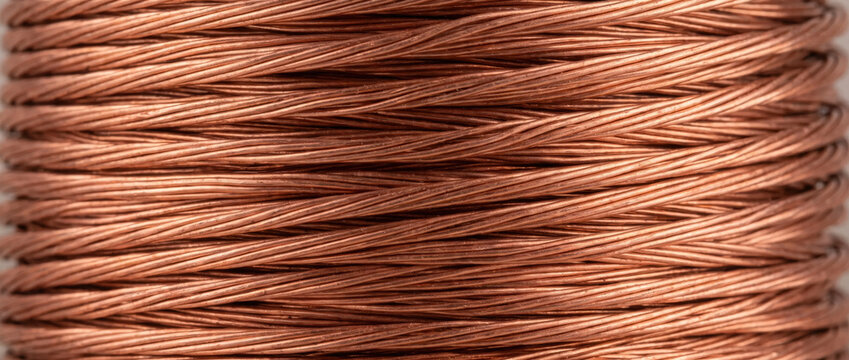 Close up of a copper wire coil. Detailed view of wound electrical cable with metallic texture. Industrial and technology background