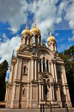 Wiesbaden, Hesse, Germany &ndash; Russian Orthodox Church of Saint Elizabeth with golden onion domes and ornate historic facade under cloudy sky.