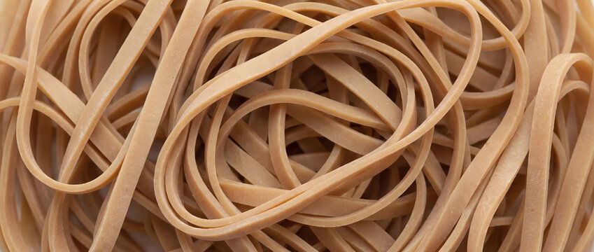 Macro of latex rubber bands pile. Tangled elastic loops background. Flexible office and school stationery supplies