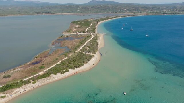 Breathtaking aerial footage of Chrisi Ammos beach and turquoise lagoon near Voidokilia, Pilos, Greece, with vivid coastline, sandbar, boats, and clear sunny skies, captured in stunning clarity.