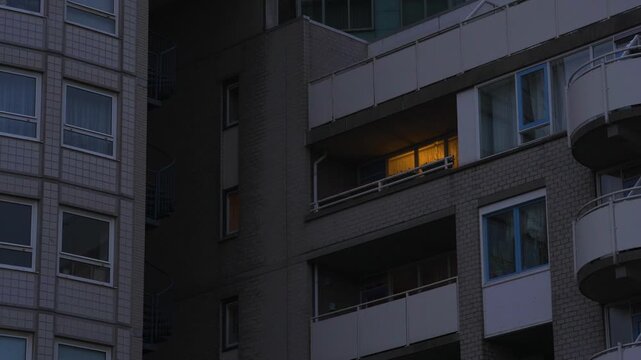 Modern apartment building with single illuminated balcony at dusk in The Hague, Netherlands, gradual zoom-in