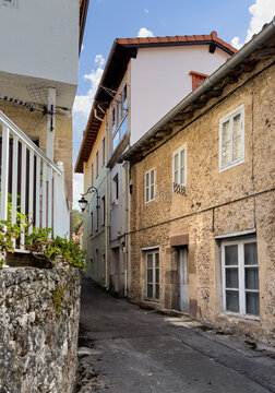Narrow village street lined with traditional old stone houses and weathered facades in a small Spanish town.