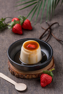 dessert in the form of caramel pudding molded in a bowl, served on a plate and garnished with sliced ​​strawberries