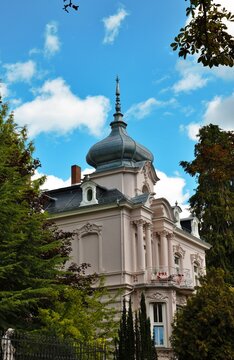 Wiesbaden, Hesse, Germany &ndash; Elegant historic villa with ornate facade, decorative balcony and distinctive domed tower framed by trees.