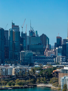 Aerial view of the Sydney skyline featuring modern CBD office towers, construction cranes, and urban redevelopment projects under a clear blue sky in Sydney, New South Wales, Australia.