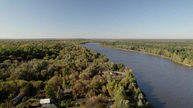 Aerial view of the Pripyat River flowing through dense forests and rural structures near Chornobyl, Kyiv Oblast, Ukraine.