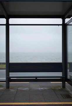 Solitude and isolation concept, empty bus stop bench overlooking a foggy sea with minimalist coastal landscape and moody atmosphere for travel themes