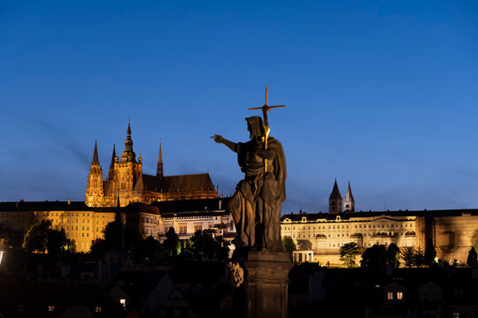 Statue of Saint John the Baptist points at Prague Castle at night
