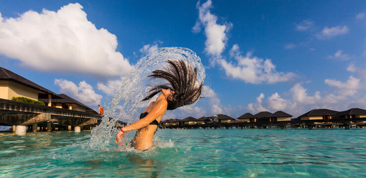 Maldives, Young woman splashing wet hair in lagoon