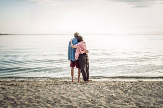 A loving couple hugs and looks at the sea on a summer beach