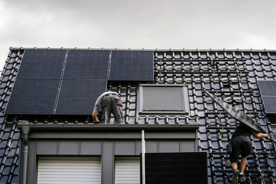 Manual worker installing solar panel on tile roof for modernization