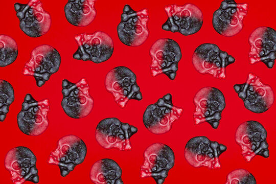 A red and black skull gummy candy pattern covers a red background