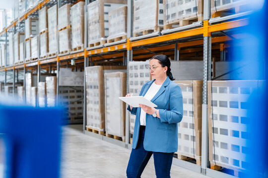 Woman manager checking inventory with a tablet in a warehouse