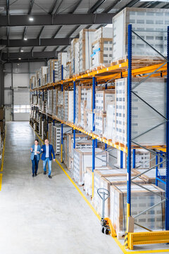 Man and woman discuss logistics while walking in a warehouse