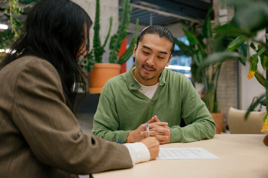 Colleagues discussing and signing contract for new job in office