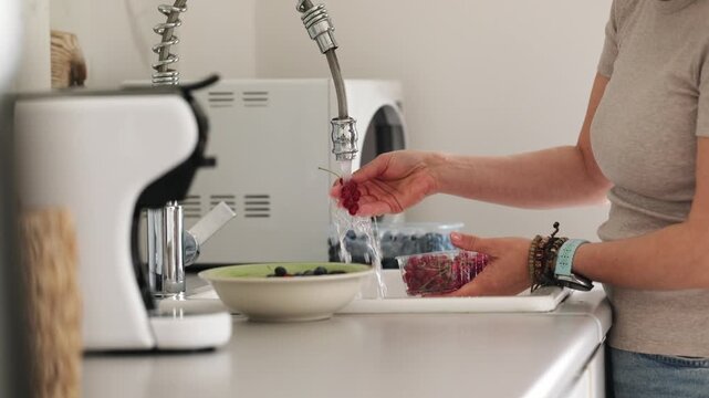 Close-Up Of Woman Washing Red Currants Under Running Water