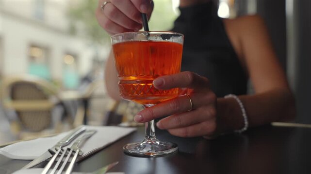 Close up of woman stirring orange cocktail at Paris cafe