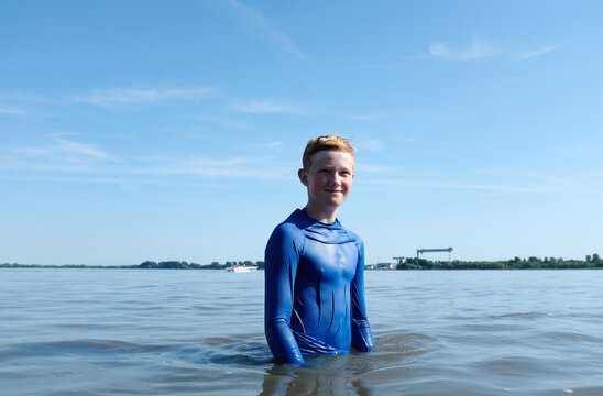 Boy in blue rash guard enjoys swimming in the river Elbe outdoors