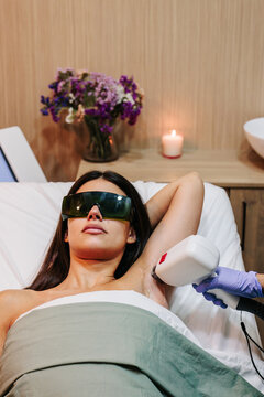 Cosmetologist performs underarm laser hair removal on a woman