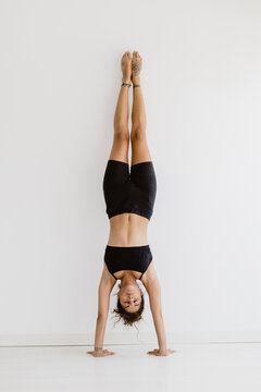 Woman performs a handstand yoga pose indoors at the studio