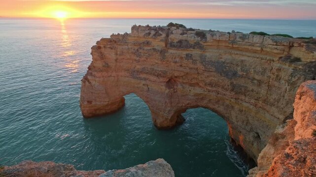 Sunrise view of Praia da Marinha beach in Algarve, Portugal, with ocean cliffs, sea stacks and golden horizon light