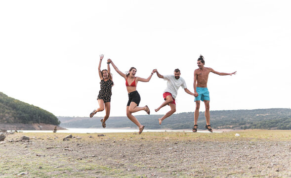 Carefree male and female friends jumping at lakeshore
