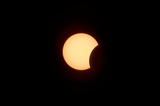 The moon partially covers the glowing sun during a solar eclipse