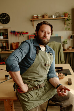 Bearded artisan holds a thread inside his workshop