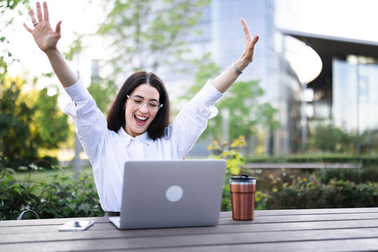 Businesswoman celebrates success with laptop outdoors